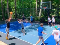Example of a small SnapSports tiled basketball and pickleball multicourt surface in shades of blue and grey, with a slew of kids in action enjoying it.